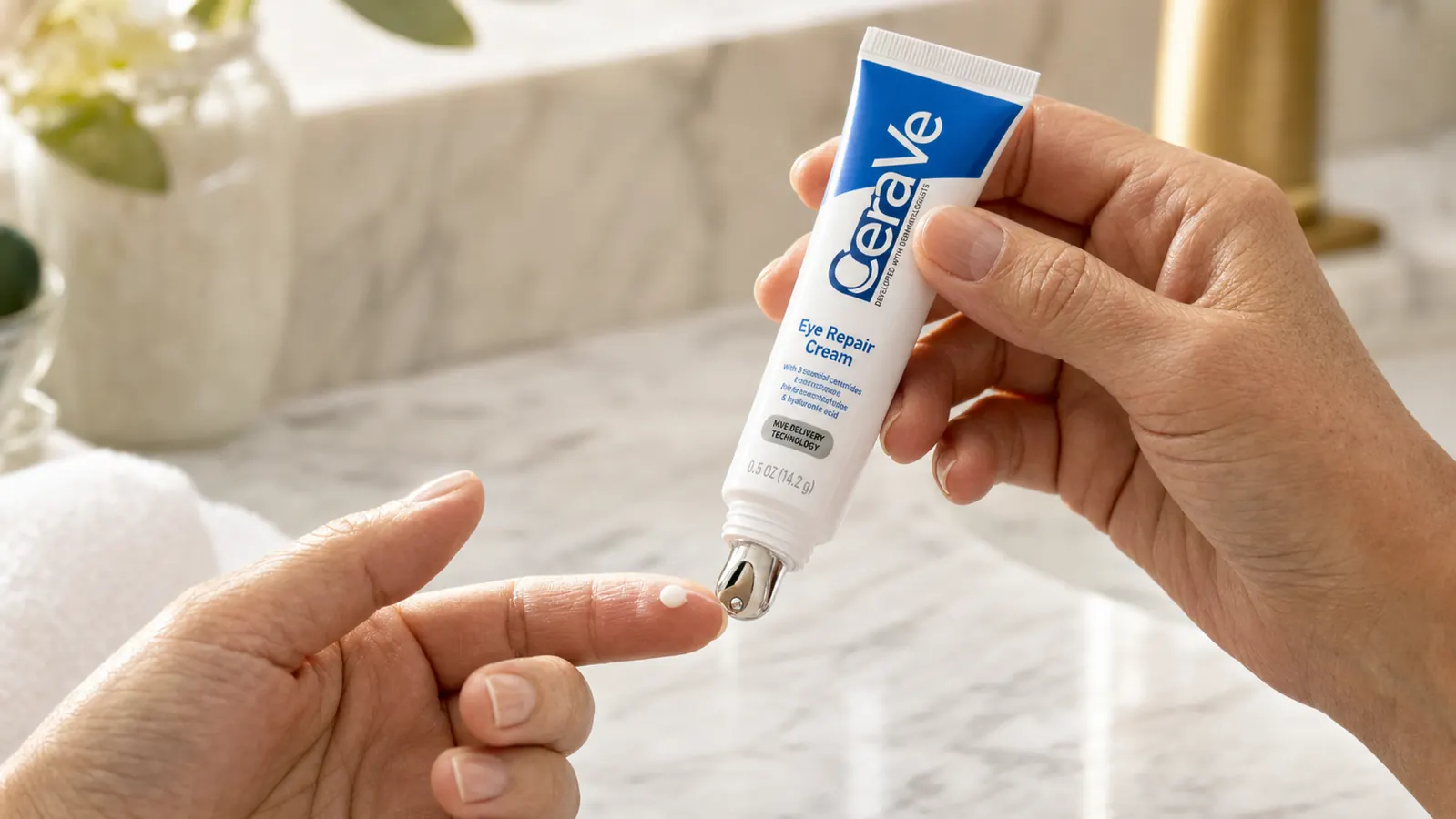 Hand dispensing CeraVe Eye Repair Cream from its metal-tip pump onto a fingertip