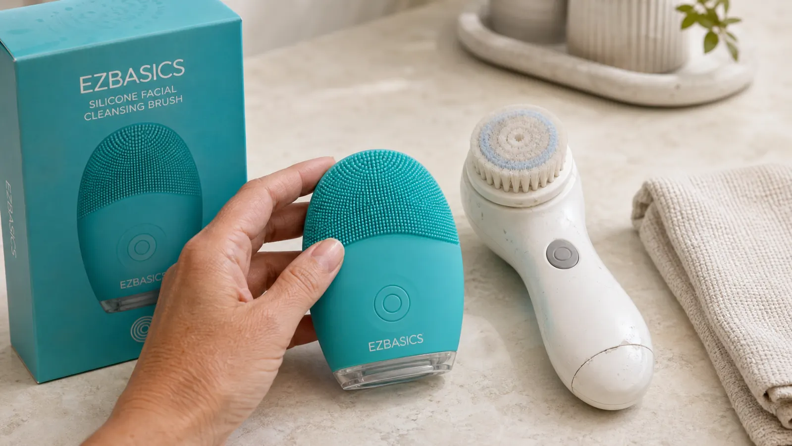 Close-up of the EZBASICS silicone cleansing brush lying next to an older, cracked plastic rotating brush handle on a bathroom counter